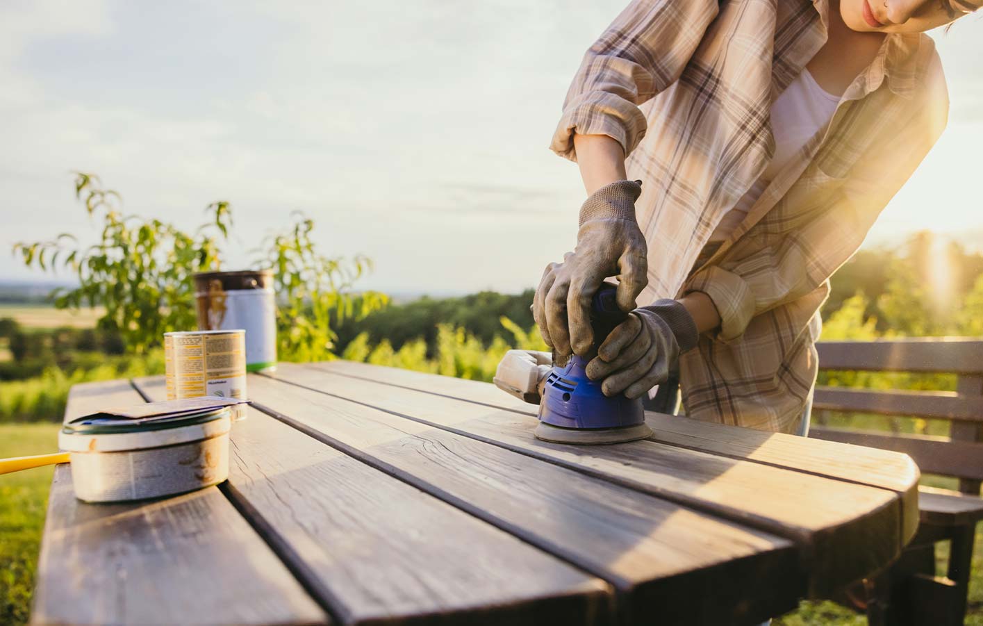 Frau schleift Gartentisch aus Holz ab