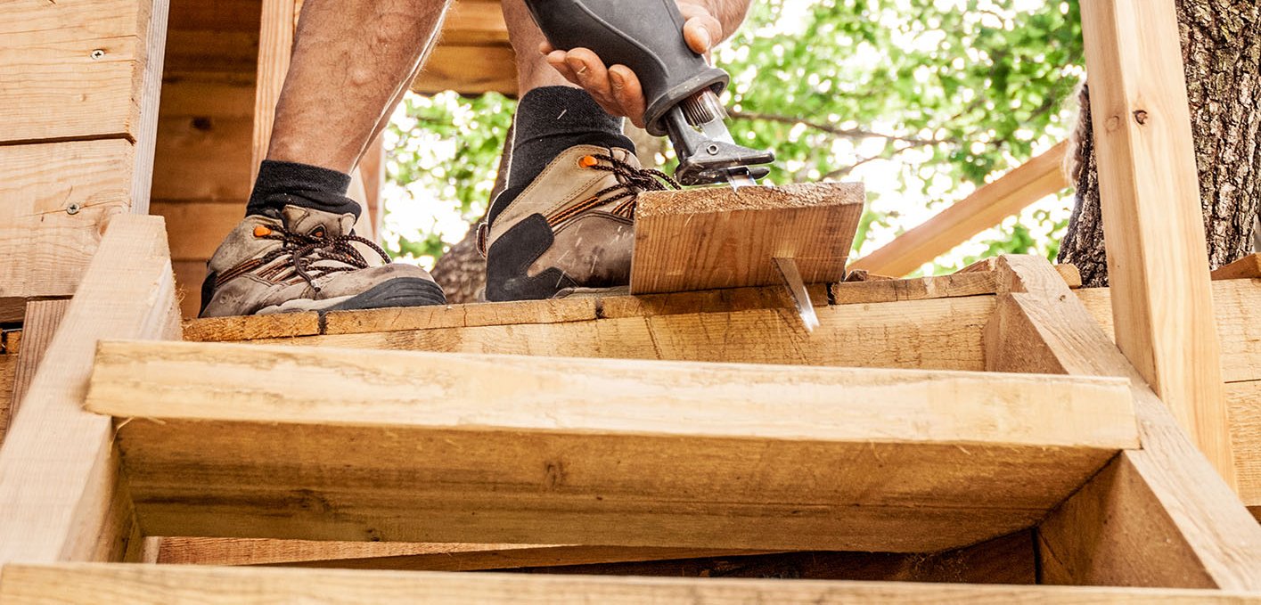 Ein Mann baut ein Baumhaus aus Holz 