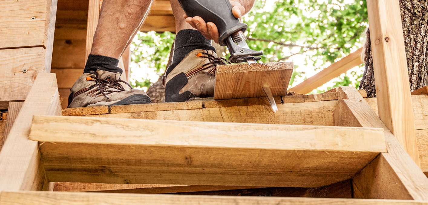 Ein Mann baut ein Baumhaus aus Holz 