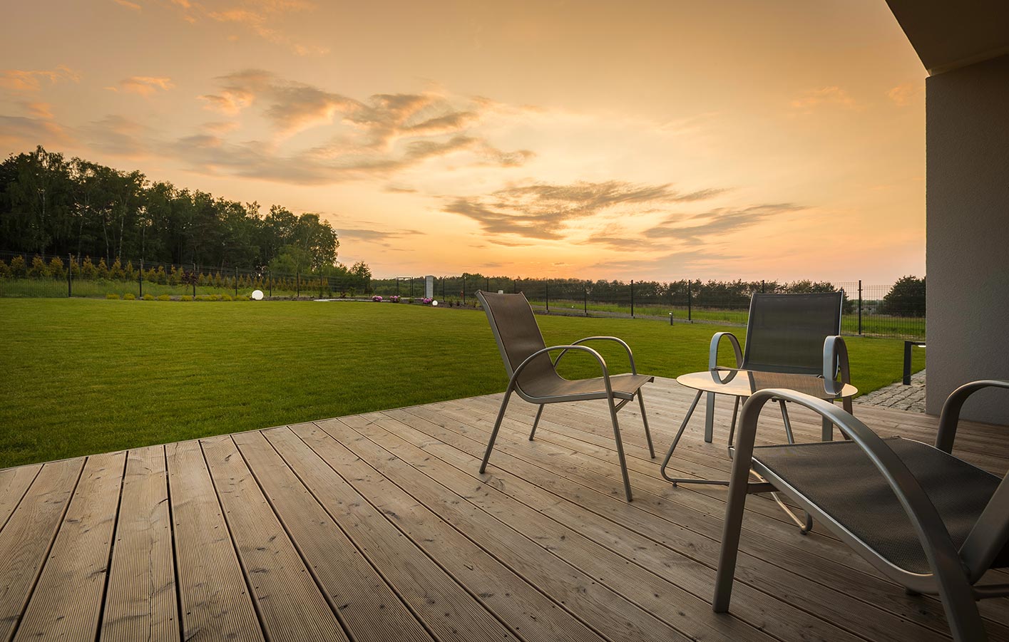 Holzterrasse mit einem Ausblick auf eine Wiese