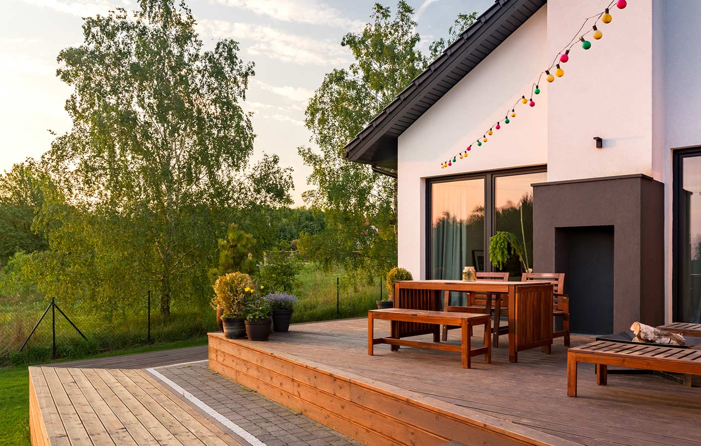 Holzterrasse mit Gartenmöbeln aus Holz vor einem Haus