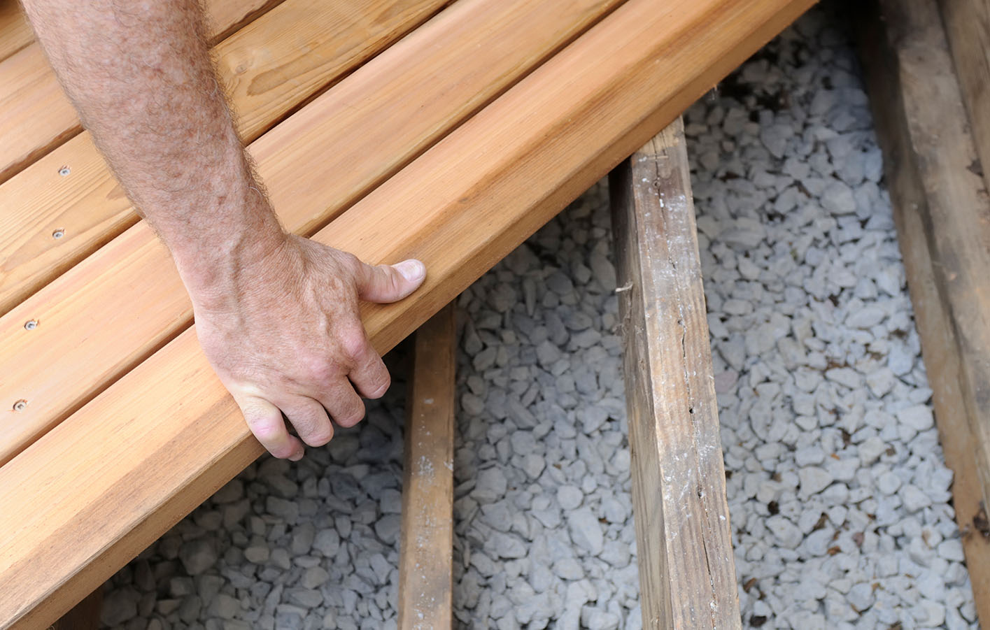 Mann verlegt Terrassendielen aus Holz