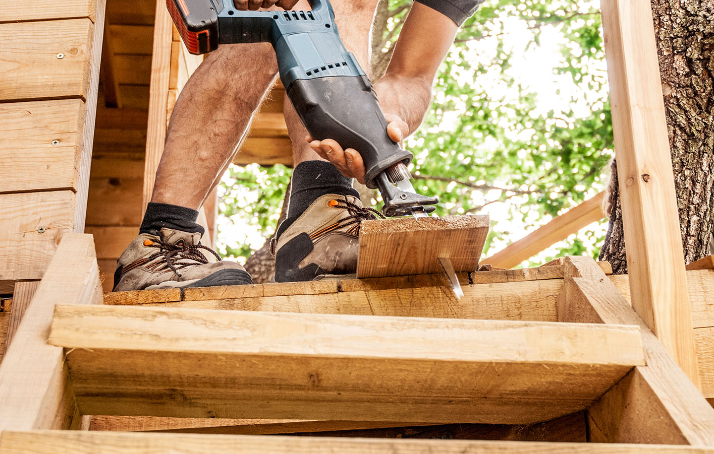 Ein Mann baut ein Baumhaus aus Holz 